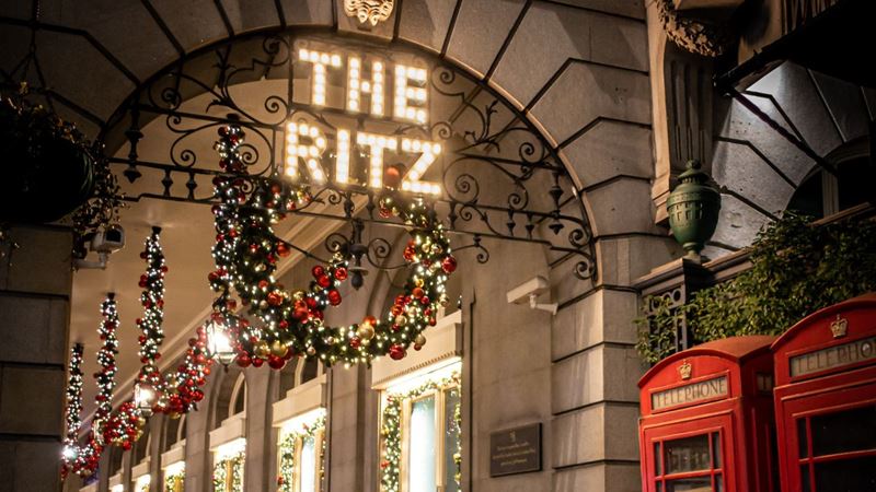 Have the most magical evening in London at The Ritz. Credit: Kate Olfans. Image courtesy of Unsplash. The lights of the ritz hotel in london with holly wreaths and a red phone box.
