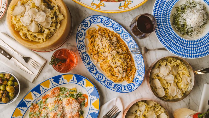 Pick from the tantalising Sicilian menu at Circolo Popolare. Credit: Joann Pai. Image courtesy of Circolo Popolare. Sicilian pasta dishes laid out on a table in colourful plates, with olives and glasses of wine also on the table.