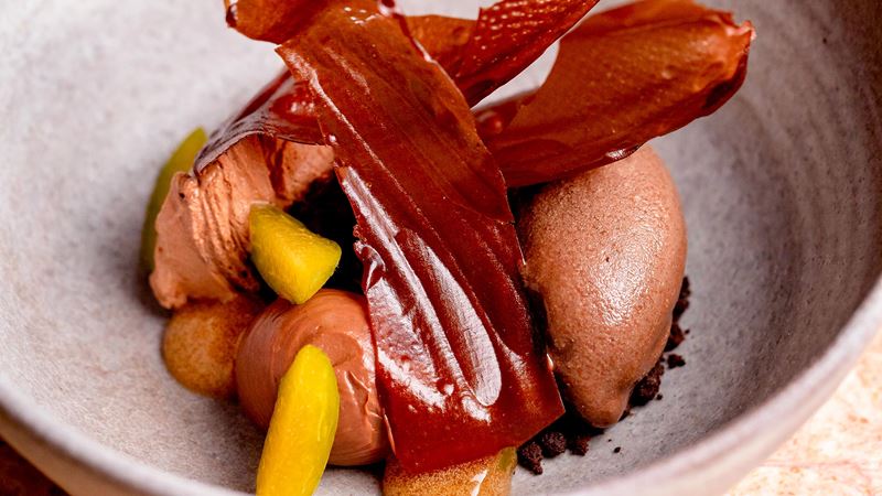 Savour every bite of your Michelin-starred meal at Hélène Darroze at The Connaught. Credit: The Connaught. Image courtesy of The Connaught. Shards of milk chocolate, chocolate ice cream and yellow fruit, assembled creatively in a bowl at Hélène Darroze at The Connaught.