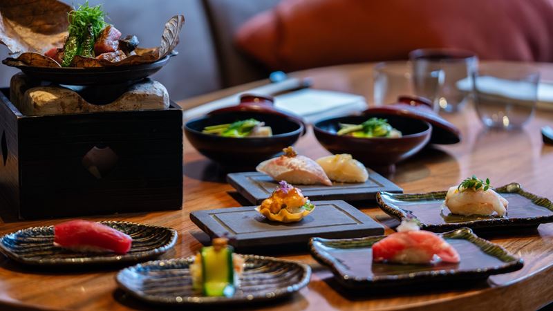 Tuck into a traditional Kyoto-style dinner at Michelin-starred Umu. Credit: Umu. Image courtesy of Umu. A selection of Japanese sushi dishes on a wooden table, including salmon, tuna and other fish and vegetables.