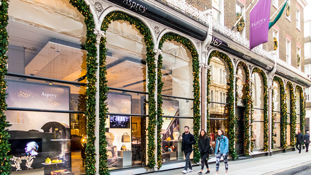 Find luxury brands at shops on Bond Street in London. Image courtesy of Shutterstock. People walking past glass window shop fronts on Bond Street in London's Mayfair.