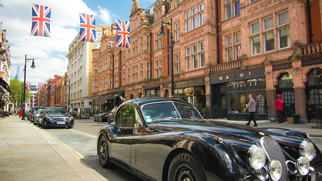 Mount Street in London's Mayfair. Image courtesy of Grosvenor Property UK. Expensive black cars parked on stylish Mount Street in London's Mayfair, with UK flags hanging between red-brick buildings in the background.
