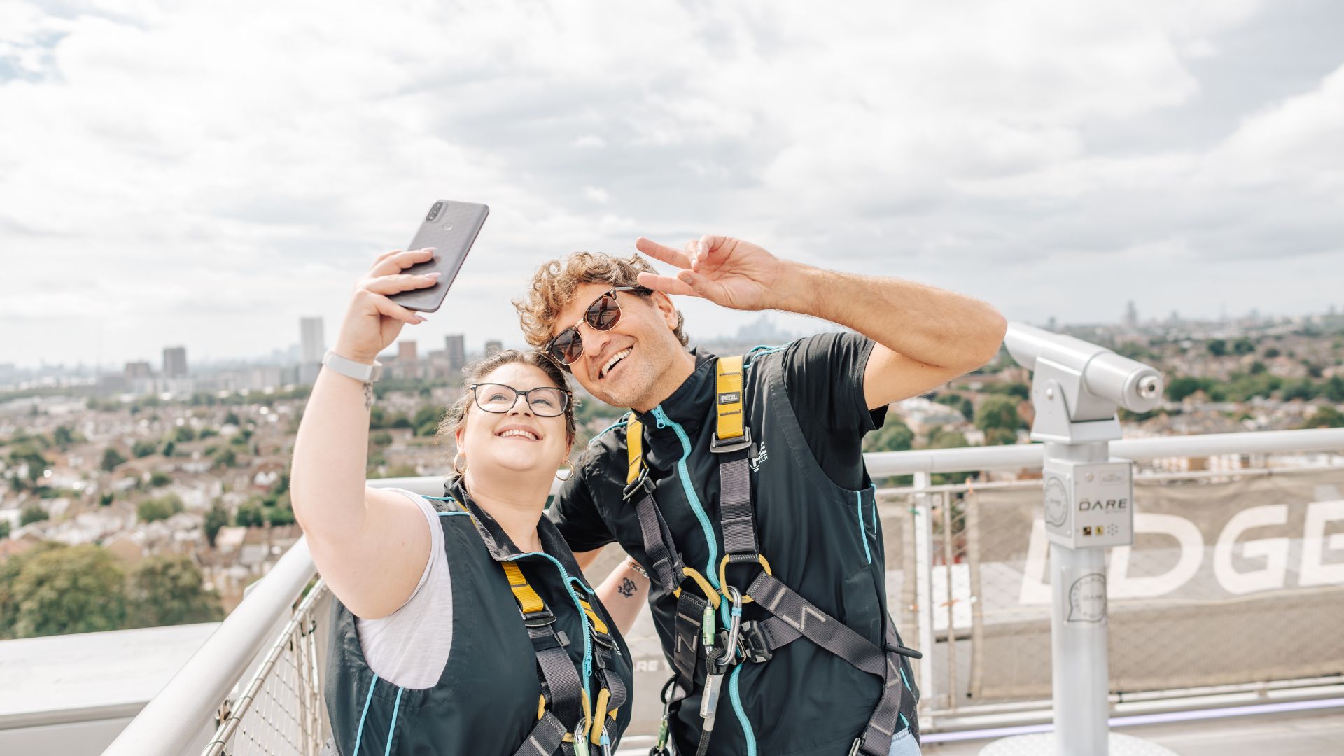 Take Father’s Day to new heights with the DARE Skywalk at Tottenham Hotspur Stadium — climb above the iconic stadium and soak up sweeping London views on this adrenaline-fuelled experience. Phone credit: London & Partners. Two people wearing safety harnesses take a selfie while completing the DARE Skywalk experience at Tottenham Hotspur Stadium, with panoramic views of London in the background.