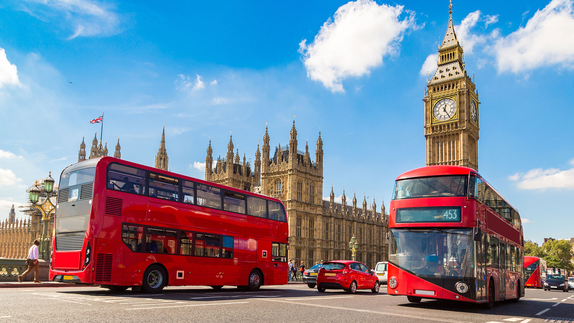 Prenez le bus à impérial et arrêtez vous à Westminster pour admirer Big Ben et visiter les Maisons du Parlement. Image fournie par © Shutterstock. Deux bus à impérial rouge passent par Big Ben et les Maisons du Parlement par une journée ensoleillée.