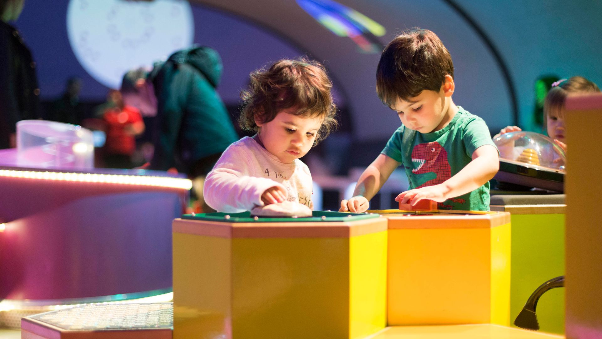 Let your toddlers get hands-on at Pattern Pod at the London Science Museum. Image courtesy of Science Museum. Two children play with toys on a yellow stand in the Pattern Pod at the London Science Museum.