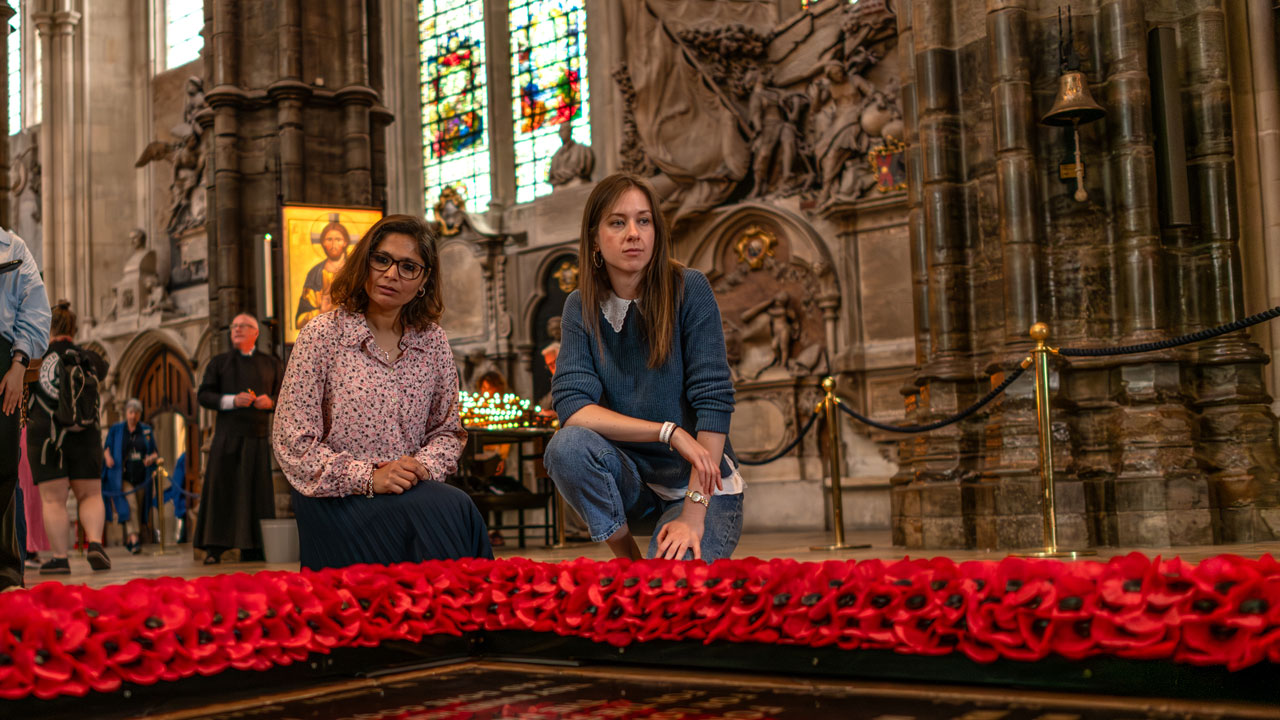Visitez l'abbaye de Westminster et trouvez la plaque commémorant la vie du Soldat Inconnu. ©London & Partners/Michael Barrow Deux femmes sont accroupies et observent la plaque du Soldat Inconnu à l'abbaye de Westminster.