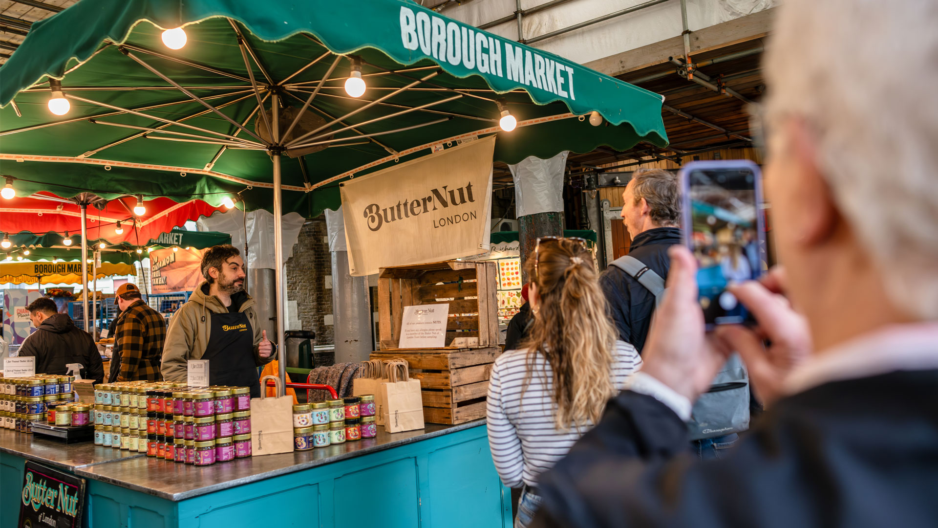 Pick up delicious from a global mix of food at Borough Market. Image courtesy of London & Partners. Man taking a picture of a stall named ButterNut London at Borough Market.