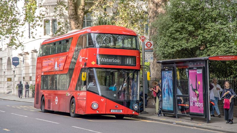 Buses run frequently from stops across London by day and night. Credit: Shutterstock. Image courtesy of Shutterstock. A red double decker bus pulled up at a bus stop in London with people queuing to board