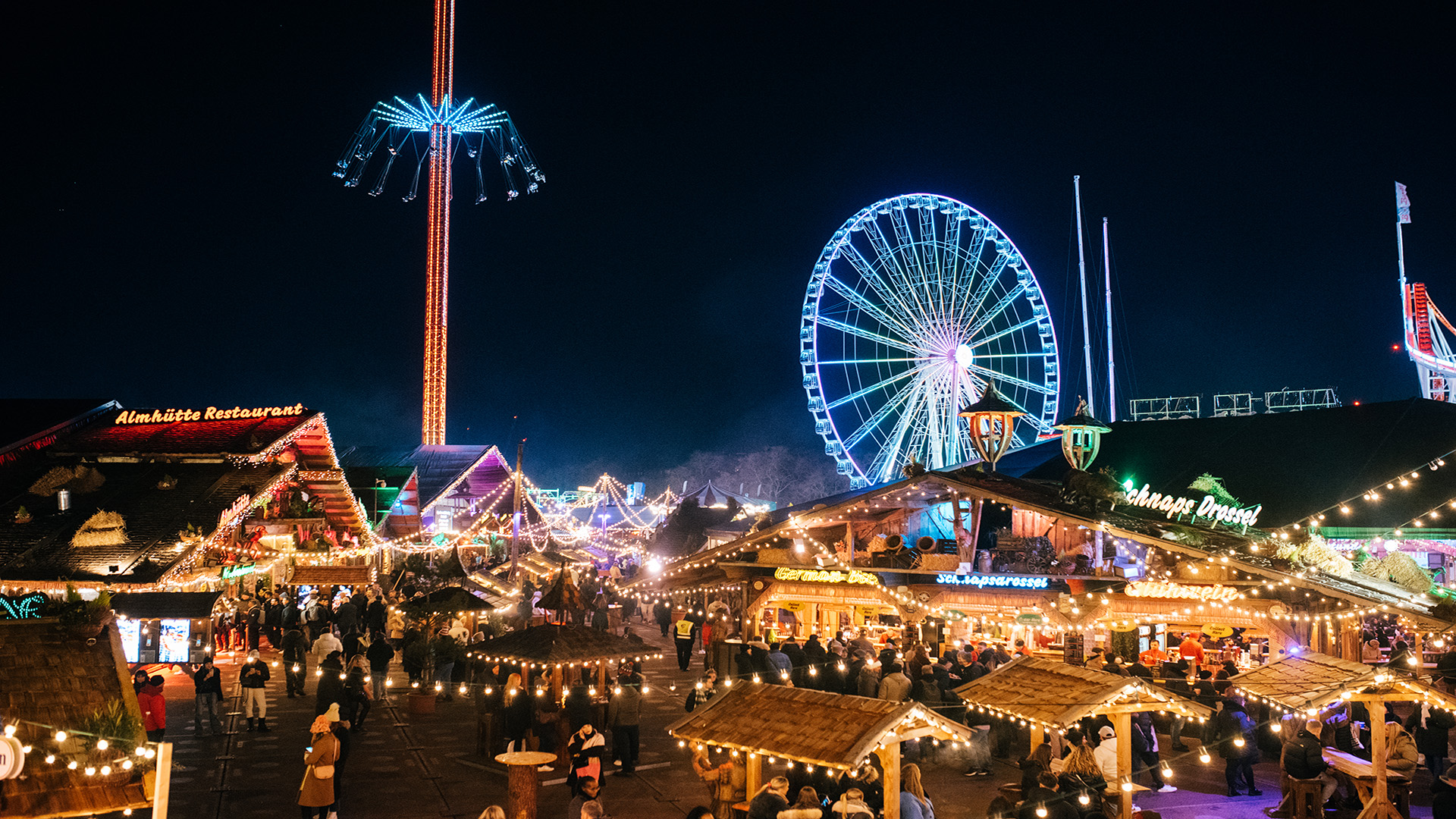 Discover Winter Wonderland in Hyde Park. Image courtesy of Winter Wonderland. Twinkling string lights hang above people perusing wooden Christmas market stalls.