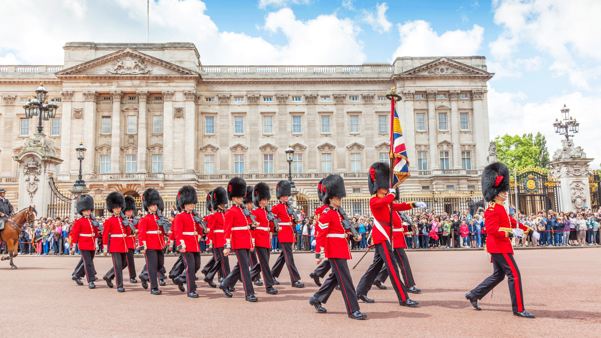 Admirez les soldats défiler devant le Palais de Buckingham lors de la cérémonie officielle de la relève de la garde. Image fournie par Shutterstock. Des soldats portant l'uniforme traditionel rouge et des chapeaux de poil d'ours forment une ligne devant le Palais de Buckingham.