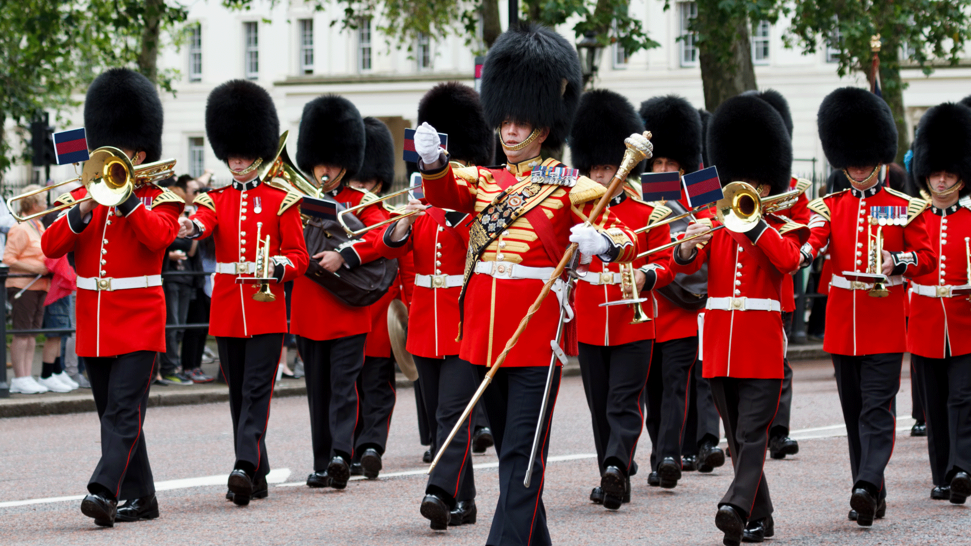 Ne manquez pas d'aller voir la relève de la garde à Buckingham Palace lors de votre visite de Londres. Image fournie par Shutterstock. Un régiment de la garde royale portant l'uniforme rouge et les chapeaux faits de poil d'ours défilent dans les rues de Londres tout en jouant des instruments de musique.