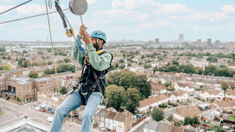 A man is equipped with a harness and securely climbs to the top of the Tottenham Hotspur Stadium.