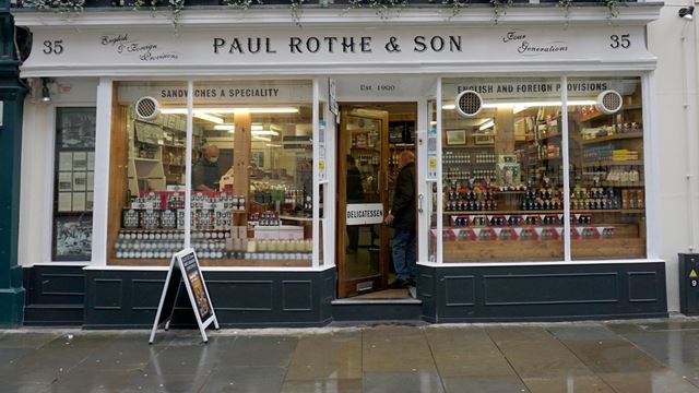 White painted exterior of Paul Rothe & Son, a deli with jars of chutney in the window.
