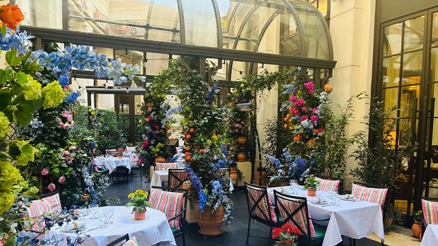 A colourful courtyard setting of tables and chairs surrounded by vibrant flowers