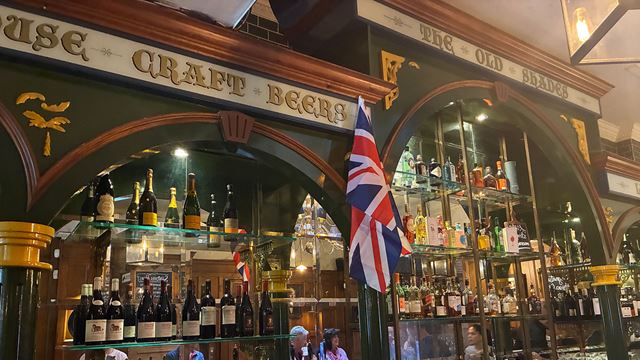 The Victorian interior of the pub with shelves behind the bar filled with bottles