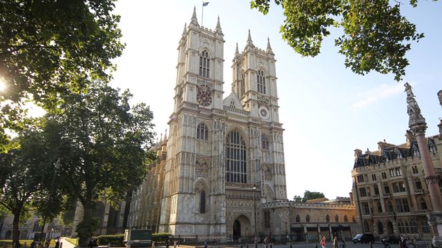 The exterior of Westminster Abbey surrounded by trees on a sunny day