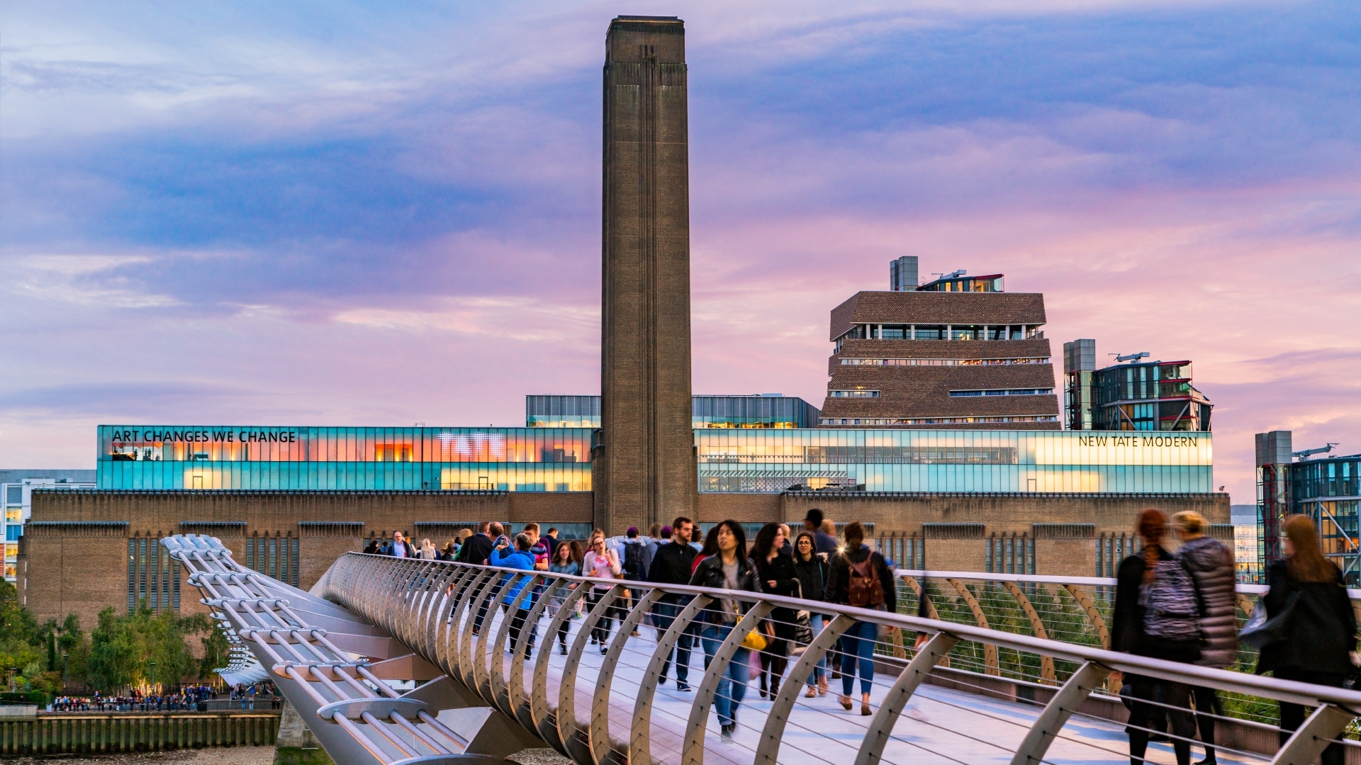 See top modern and contemporary art at Tate Modern. Credit: Jon Reid. Image courtesy of visitlondon.com. Tate Modern in the background and the Millennium Bridge in the foreground, lit by a pink sunset sky