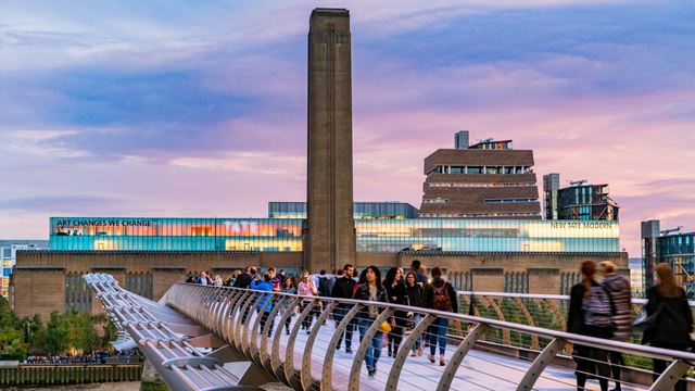 Tate Modern in the background and the Millennium Bridge in the foreground, lit by a pink sunset sky