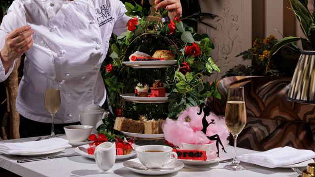 Floral-themed afternoon tea stand with cakes, sandwiches, tea and sparkling wine.