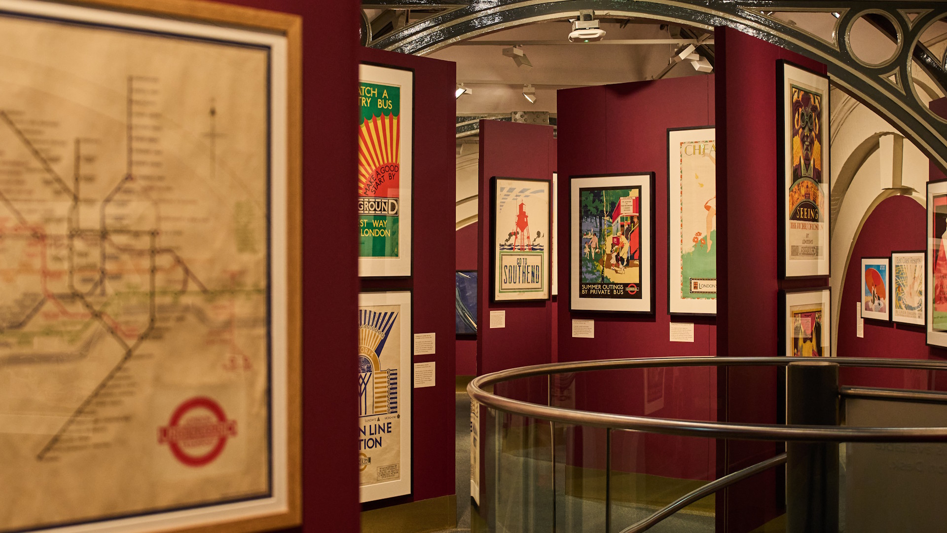 An exhibition room at London Transport Museum with a Tube map and colourful art-deco-style posters on the walls.