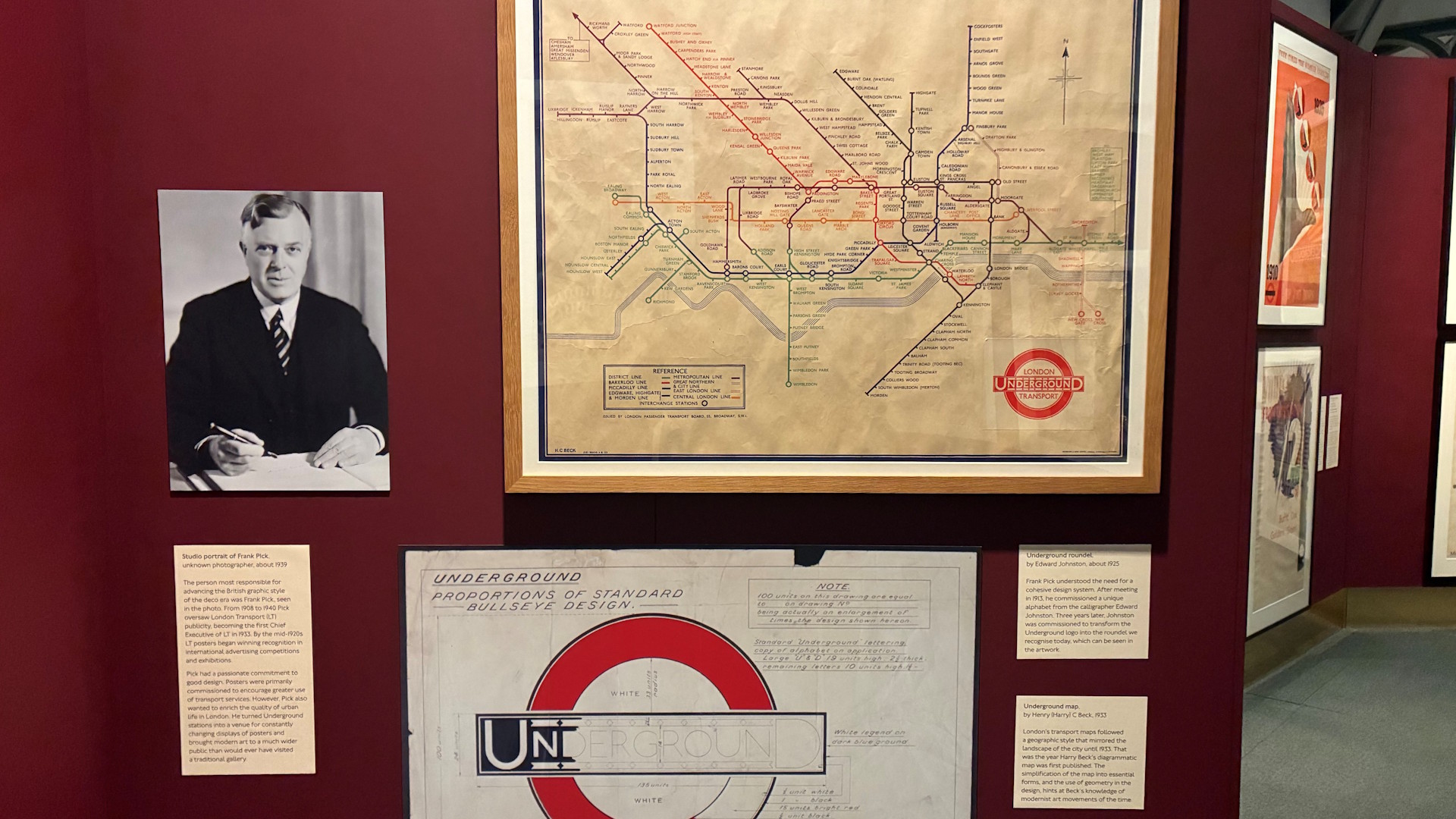 Learn more about the influence of Frank Pick on the enduring design of London Transport and the Underground. Image courtesy of Jonny Payne. An early Tube map, a partly-coloured Tube roundel and a black-and-white photograph of Frank Pick displayed on a wall.