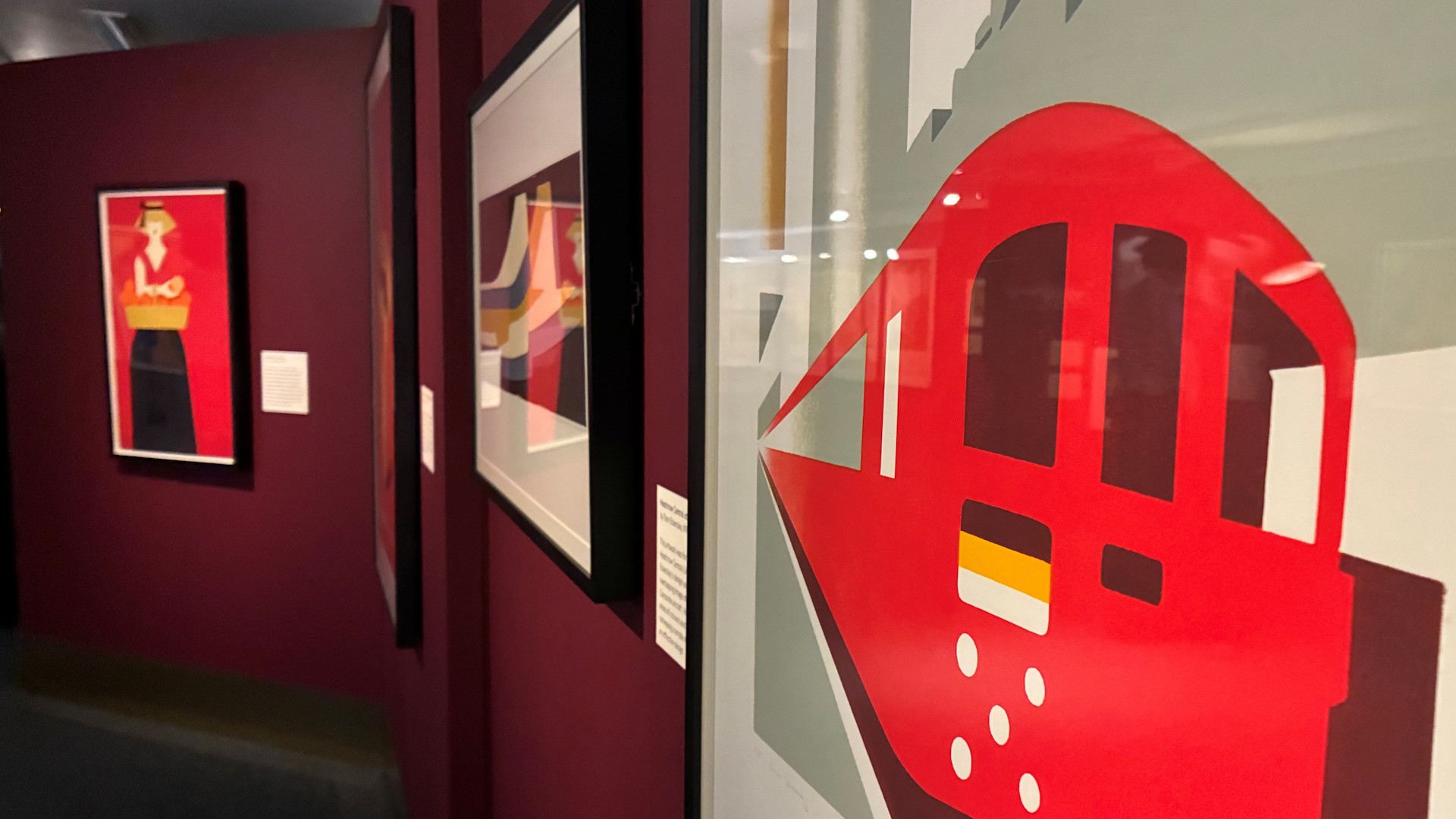 Study how art deco style principles have inspired modern-day posters, as part of the art deco posters exhibition. Image courtesy of Jonny Payne. Modern posters, including one with a red Tube train against a grey background, on display at the London Transport Museum.