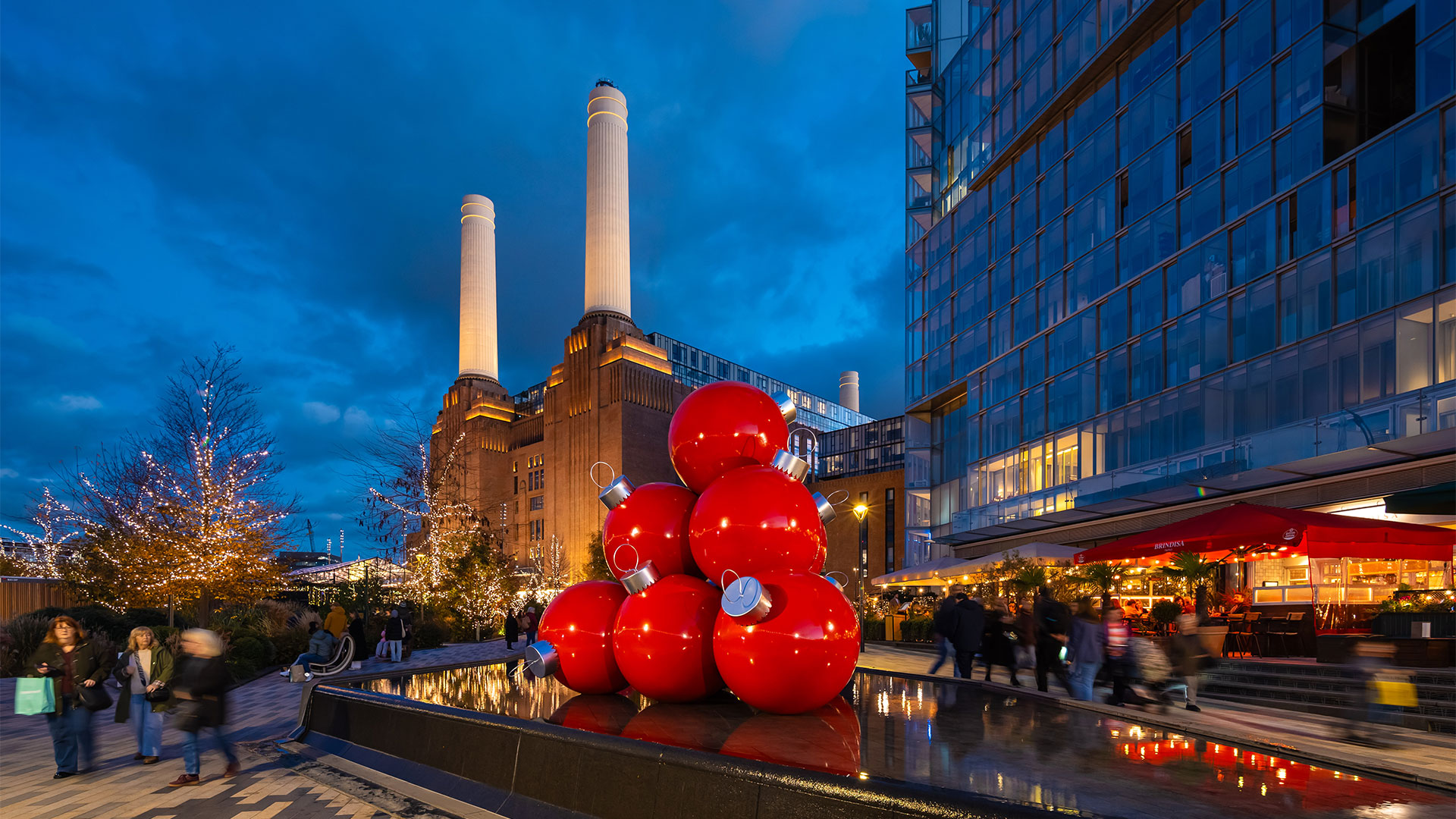 Enjoy the perfect festive day out at Battersea Power Station, all decked out for the Christmas season. Photo credit: Charlie Round-Turner. Battersea Power Station at night, with giant red Christmas bubbles arranged in the shape of a triangle.