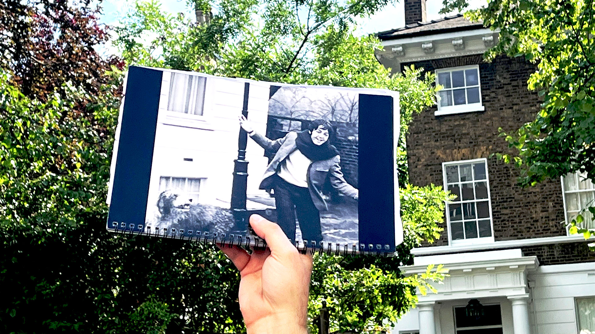 Someone is holding up a photograph of Paul McCartney with his dog, Martha, outside his home in St John's Wood.