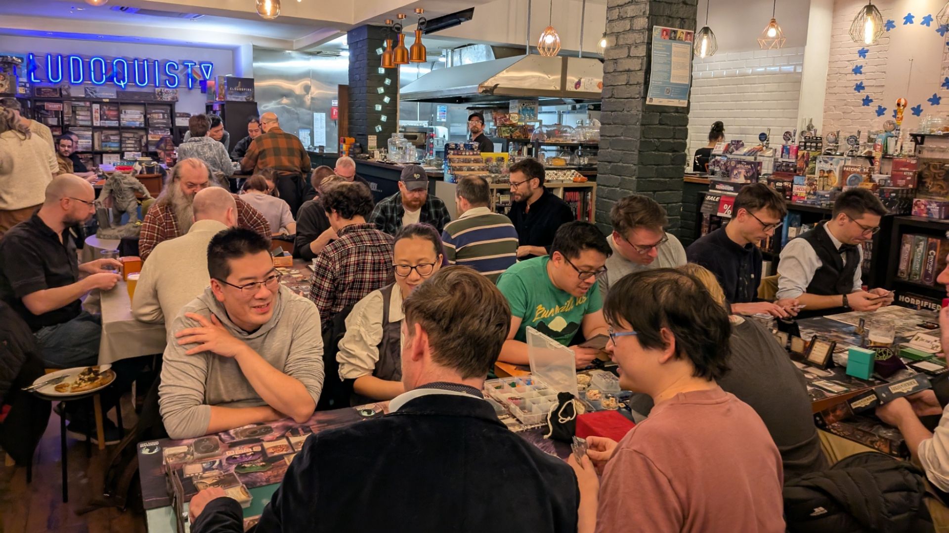 Tables full of people playing board games at Ludoquist.