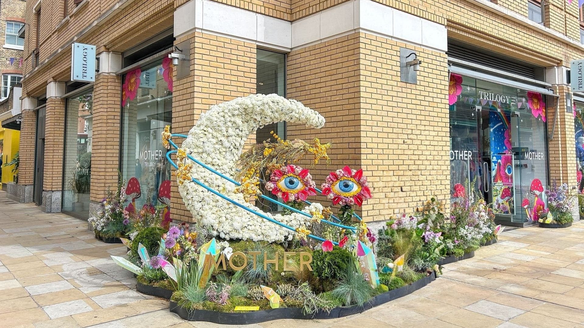 Visit Chelsea in Bloom this May and see the vibrant floral art show, London’s largest free-to-attend festival of flowers. Image courtesy of Hannah Cornish. Floral crescent moon with oversized flower “eyes” and the word “Mother” in front of a shopfront decorated with colourful blooms
