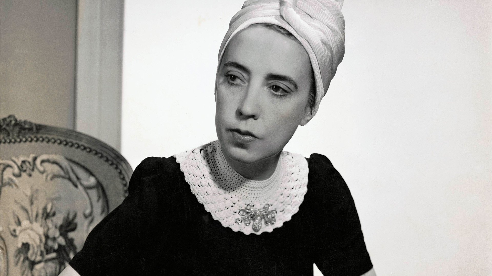Vogue 1940 showing Elsa Schiaparelli wearing a black silk dress with crocheted collar of her own design and a turban.