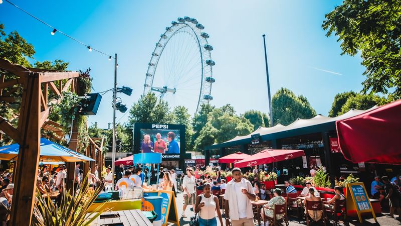 Visitors enjoy outdoor dining and a large sports screening beside the London Eye at Between The Bridges.
