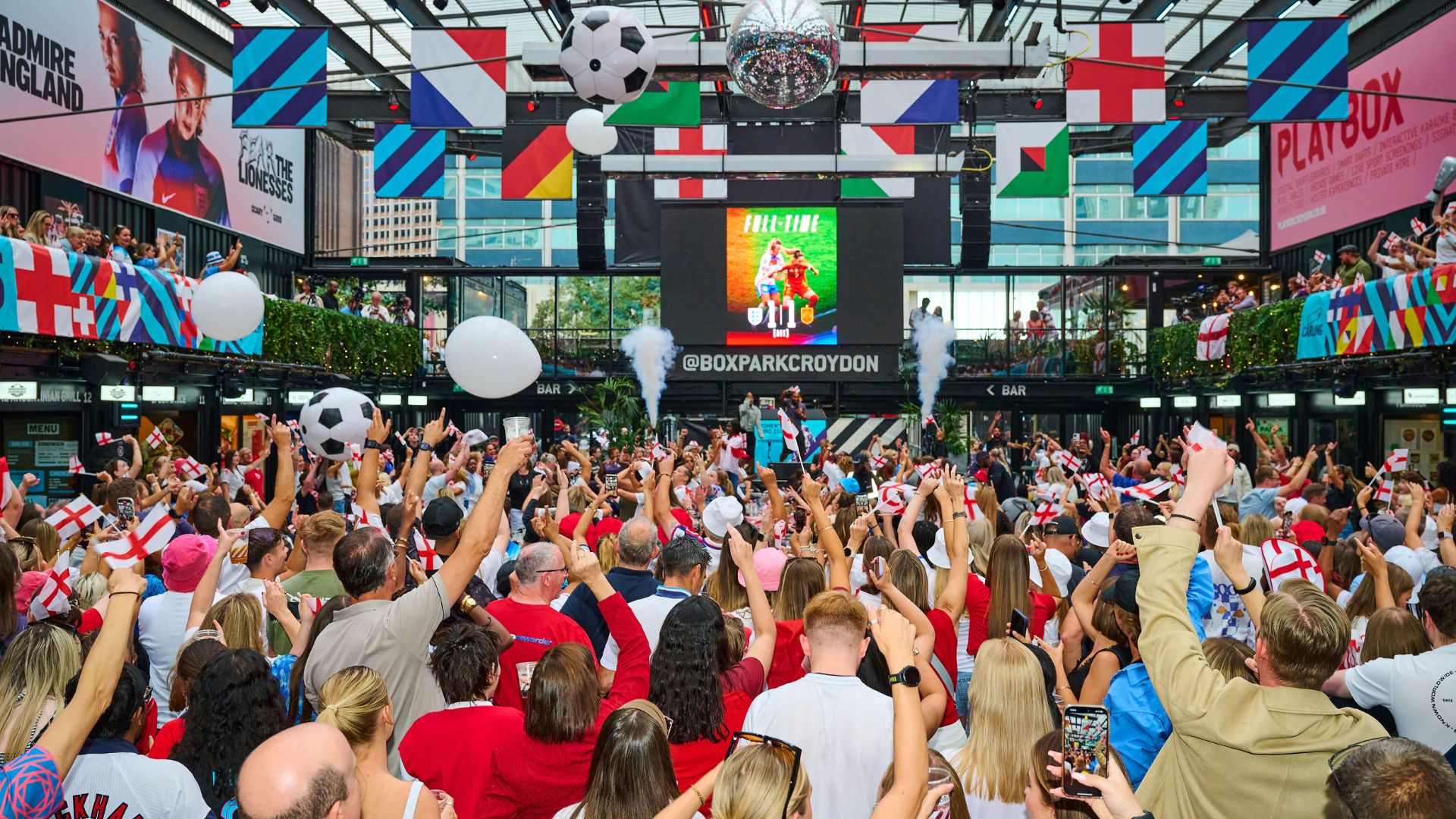 Don't miss a minute of the action at London's lively BOXPARK venues which will be showing the World Cup this summer. Image courtesy of The Fitting Room. Football fans gather in front of large screens at a viewing party at BOXPARK Croyden in London.