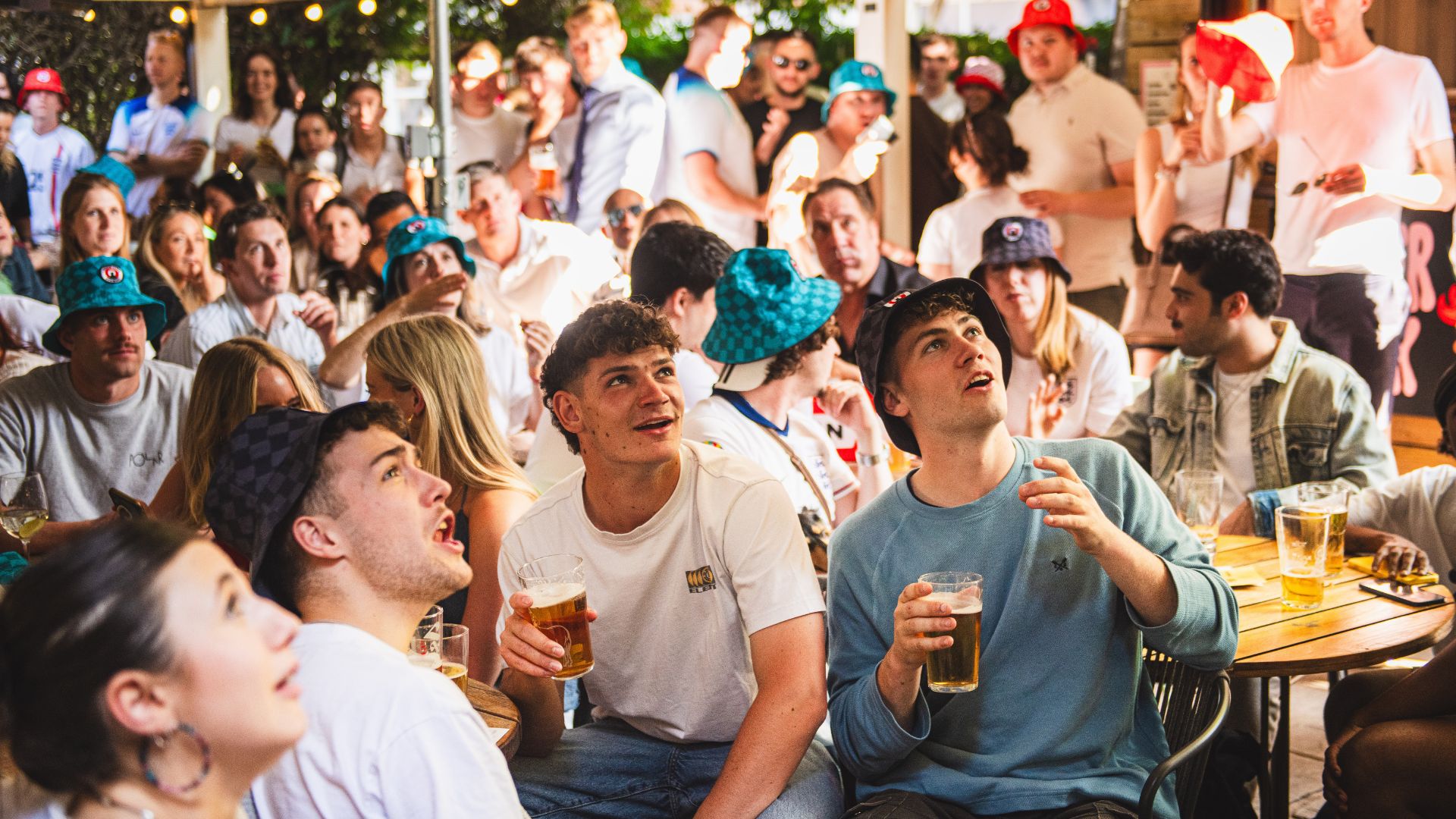 Football fans watch a match on a large screen at a London pub during a major tournament.