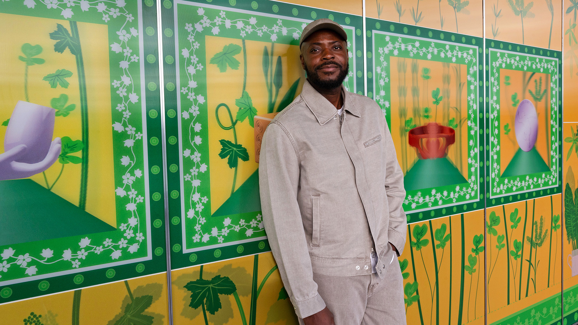 Yinka Ilori stands alongside his striking artwork on the exterior of Fulham Pier