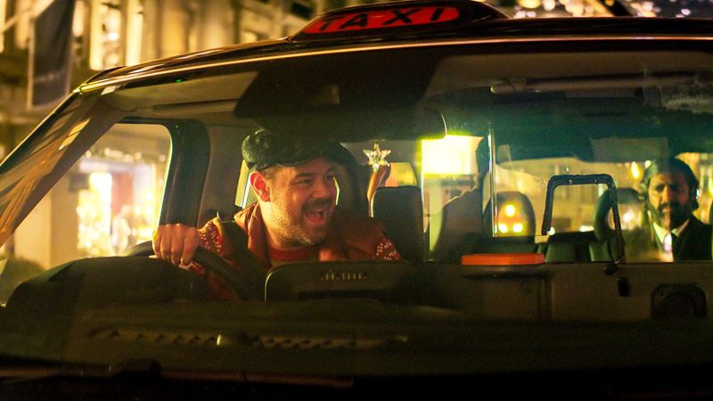 Danny Dyer in Christmas Karma. Credit: True Brit Entertainment. A still from Christmas Karma of Danny Dyer driving a black cab through London at Christmas while singing