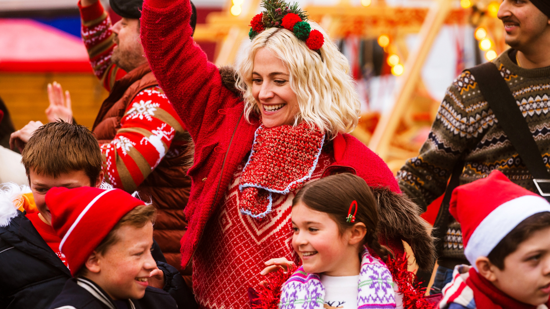 A still of Pixie Lott in Christmas Karma smiling and dressed in a festive outfit at a market with her children in the film