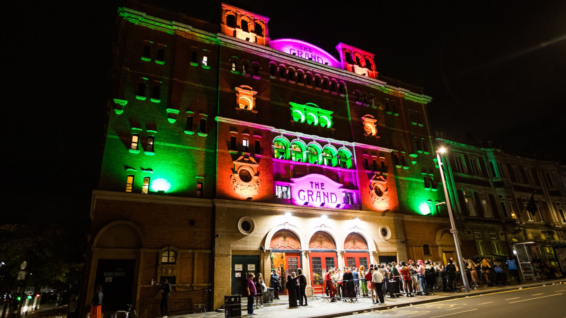 Enjoy a hair-raising Halloween club night in London at The Clapham Grand. Image courtesy of The Clapham Grand. The exterior of The Clapham Grand, lit up at night in a Halloween theme of orange, green and purple lights.