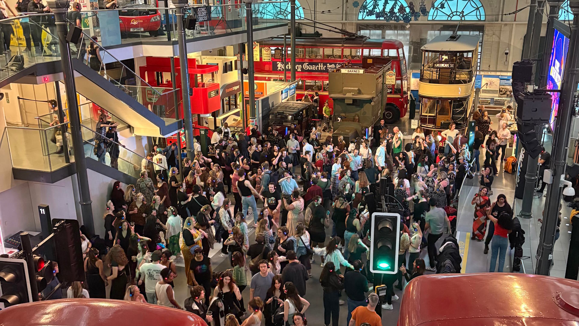 Party after hours at the London Transport Museum with Iconic Silent Disco's Halloween special. Revellers wearing headphones dance in the hall at the London Transport Museum during a silent disco, surrounded by historic London buses.