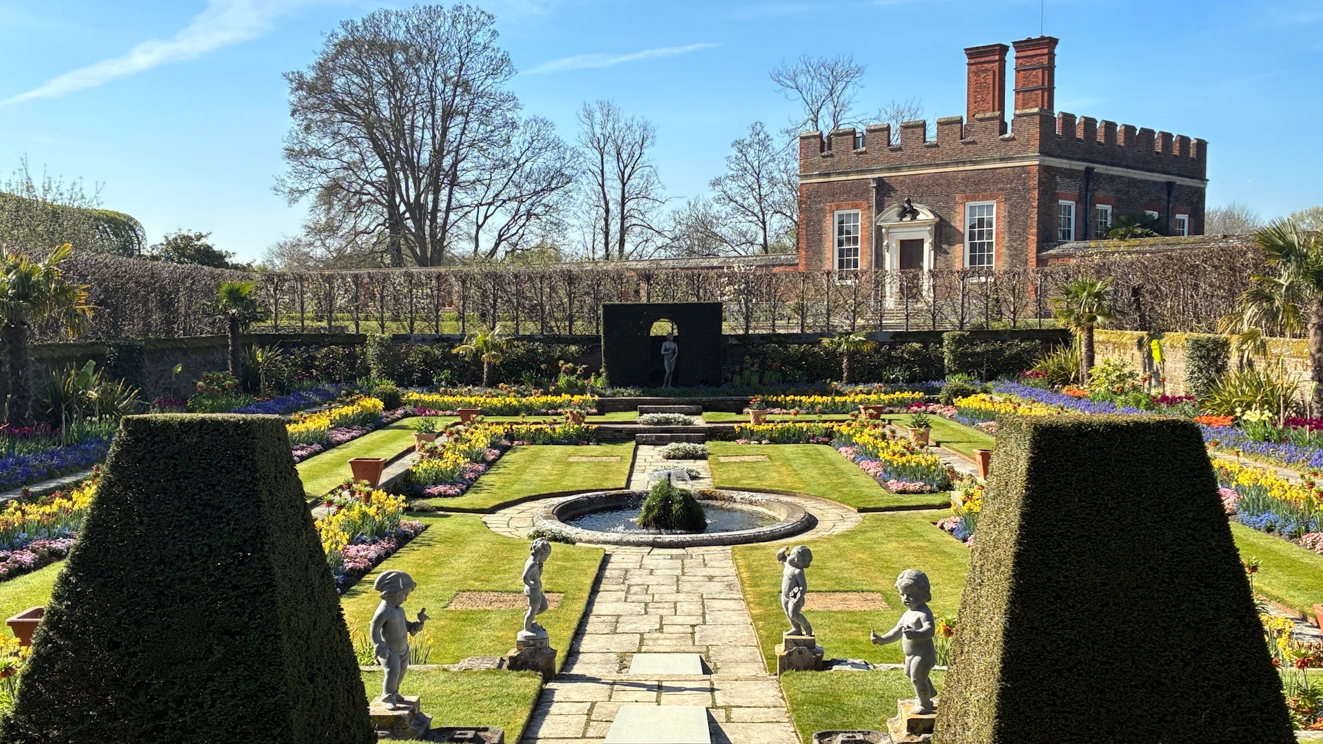 tulip-festival-hampton-court-palace-the-pond-garden-orange-quarter-1920x1080 Topiary, grass, statues and spring flowers in The Pond Garden Orange Quarter at Hampton Court Palace.