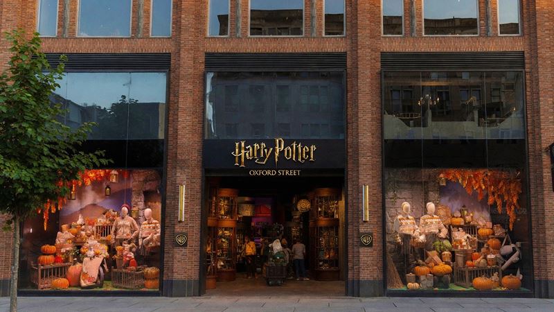 Exterior of the Harry Potter Shop on Oxford Street in London, featuring large themed display windows decorated with pumpkins, autumn foliage and wizarding merchandise.