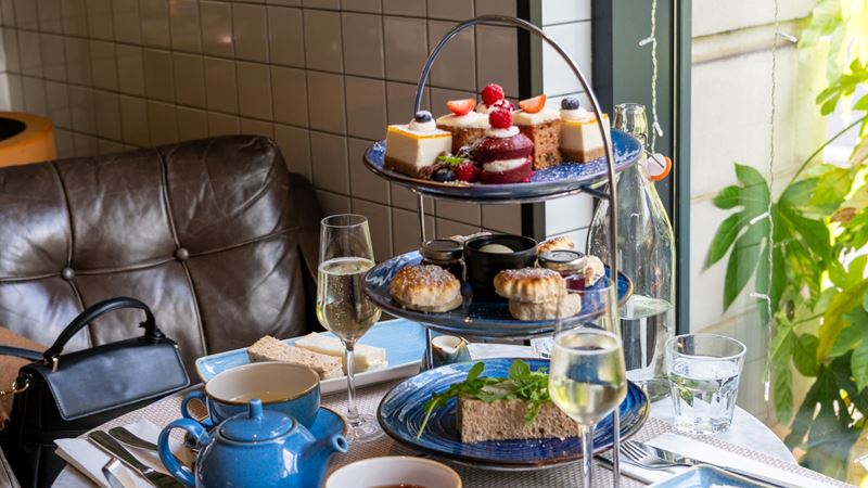 Novotel London St James afternoon tea. Credit: Jou Jou Travels. Image courtesy of Jou Jou Travels. A photo of a three tier afternoon tea platter at Novotel London St James with cakes, sandwiches, scones, a teapot and a glass of fizz