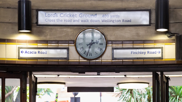 The entrance to St John's Wood Underground station taken from inside the station, showing a clock and directions to Lord's Cricket Ground.