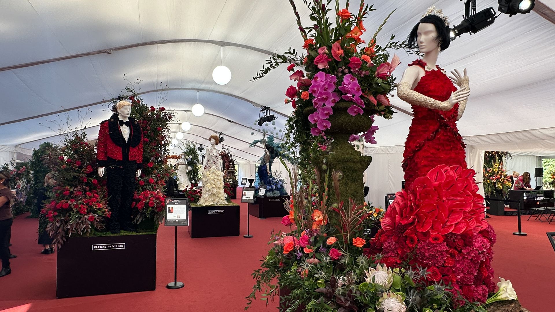 Lady Mary in a striking red floral gown beside her beloved, Matthew Crawley at the Downton Abbey exhibition at Kew Gardens. Photo Credit: Kirstine Spicer. Lady Mary in a striking red floral gown beside her beloved, Matthew Crawley in a red floral jacket at the Downton Abbey exhibition at Kew Gardens