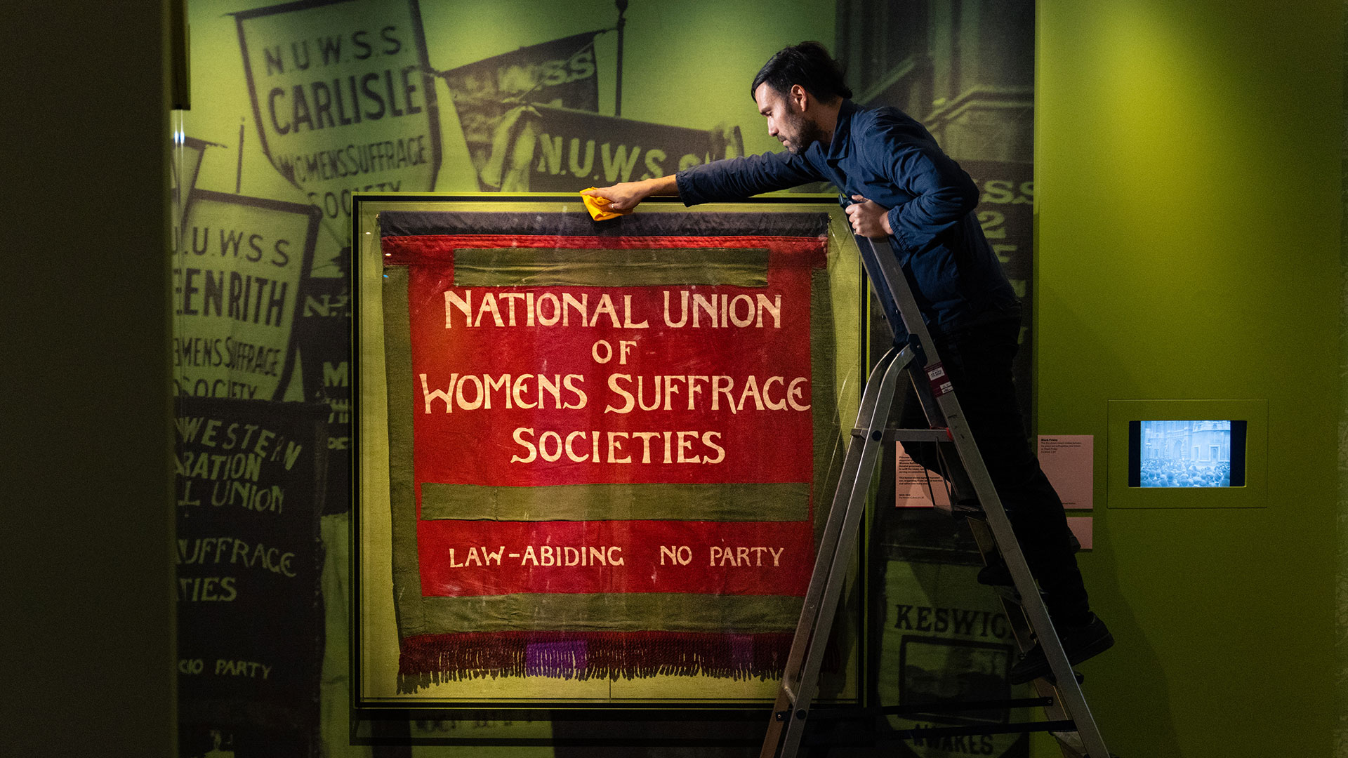 Historic Royal Palaces conservator Nelson Garcia prepares a banner used by the National Union of Women's Suffrage Societies (NUWSS) in the early 20th century, for display in a new exhibition at Kensington Palace.