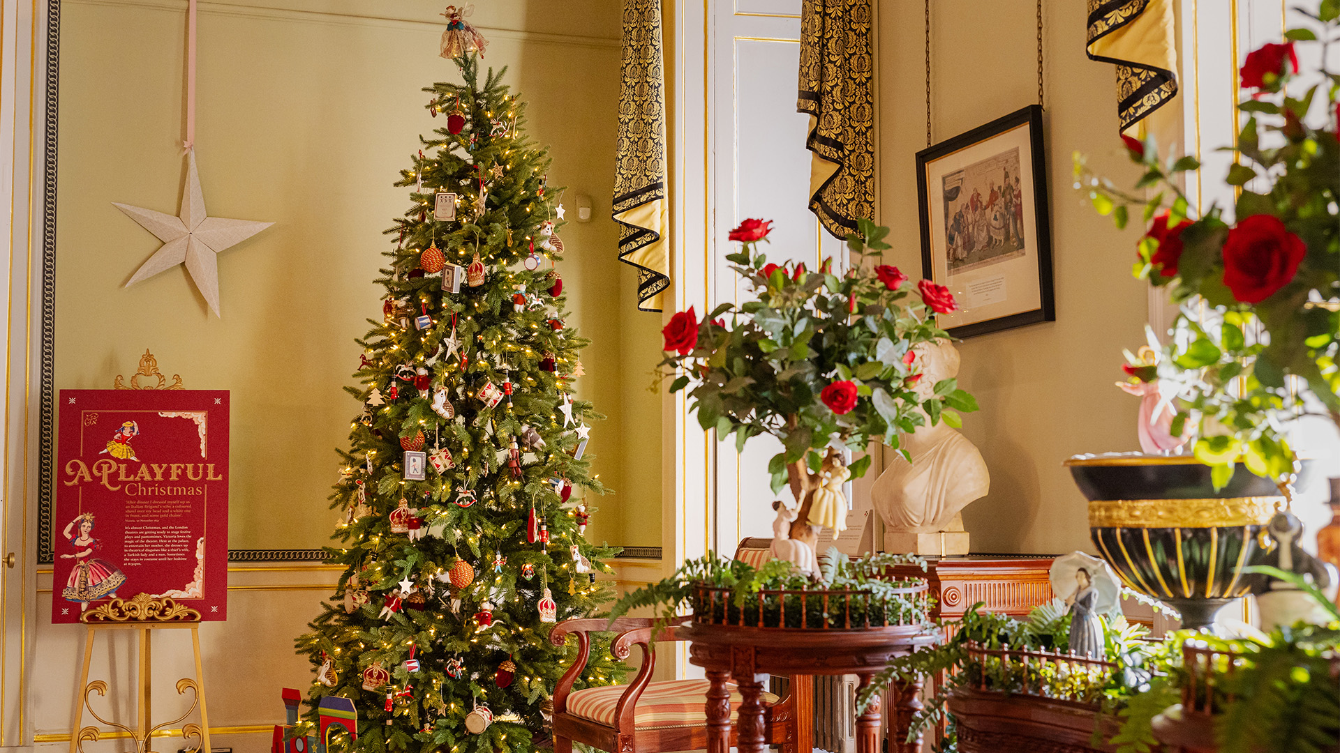 A decorated Christmas tree and side tables with flowers on them in a nicely arranged room inside of at Kensington Palace.