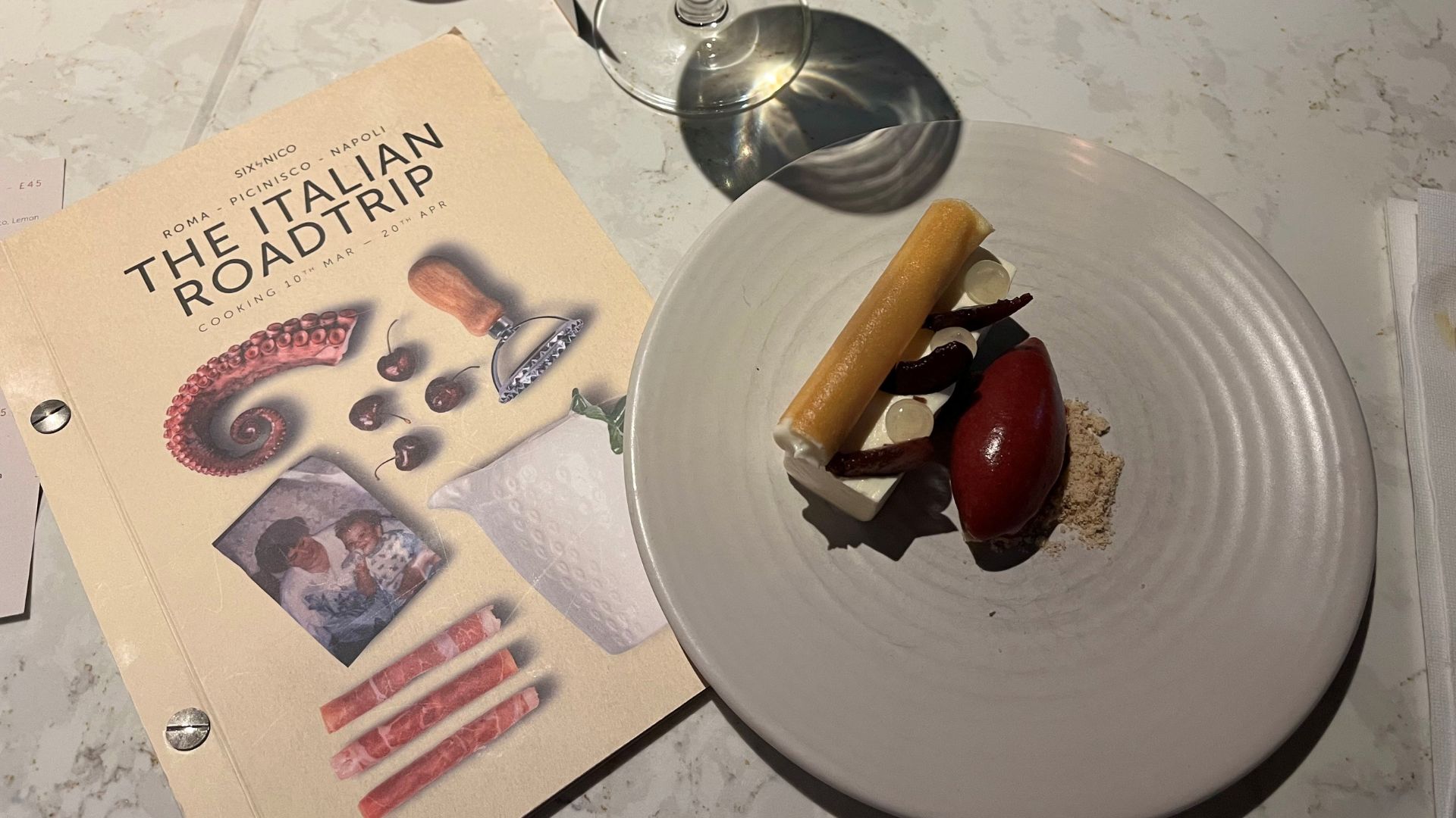A table with an italian menu and a savoury dish at the six by nico italian tasting meal.