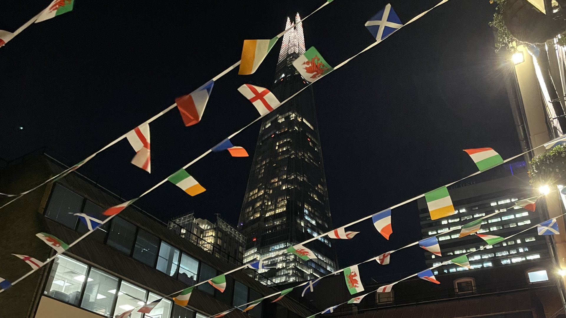 Flags of the world bunting against a night sky in London against the Shard.