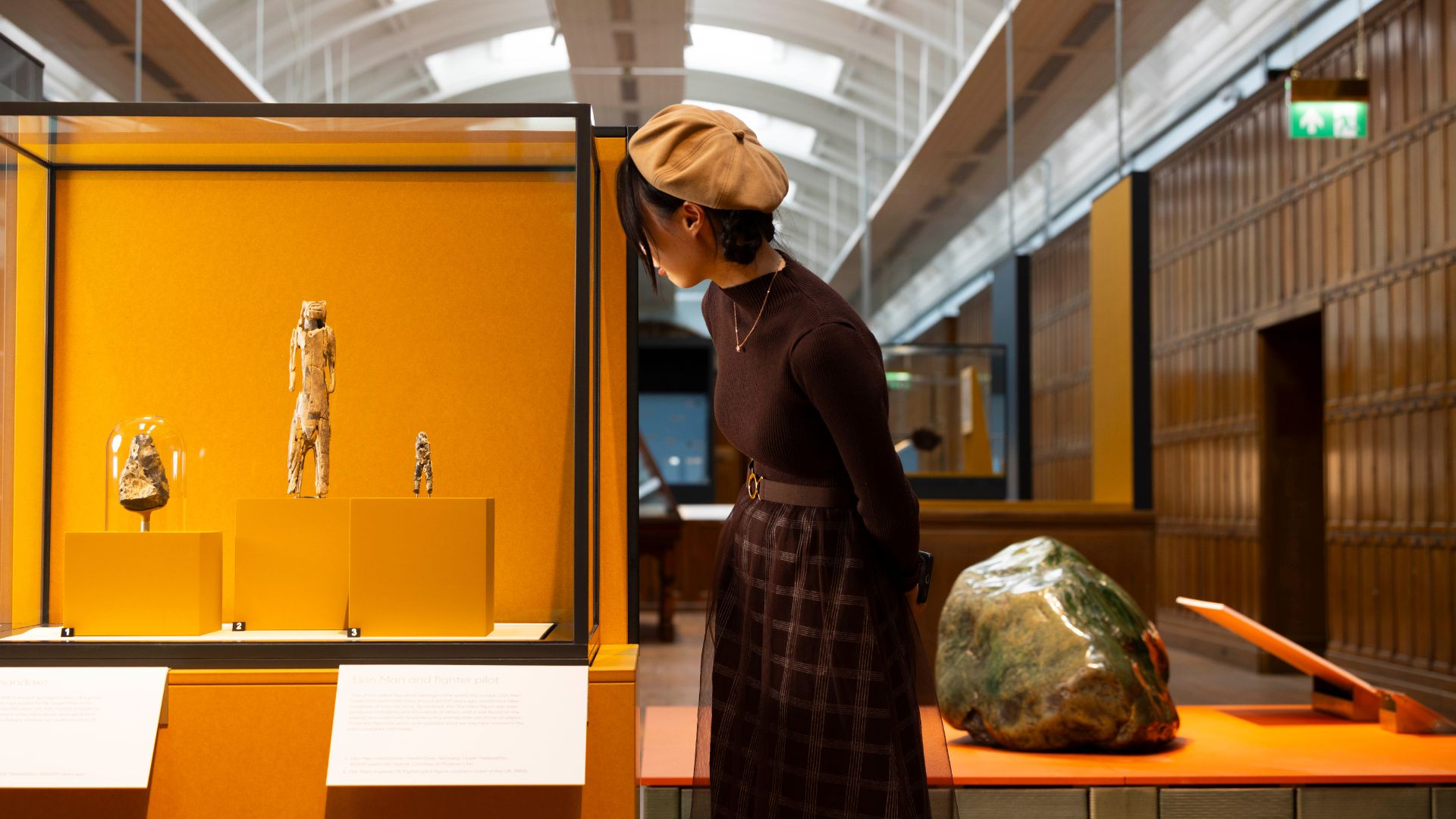 A person looking at three historic figurines in a glass case at the Natural History Museum.