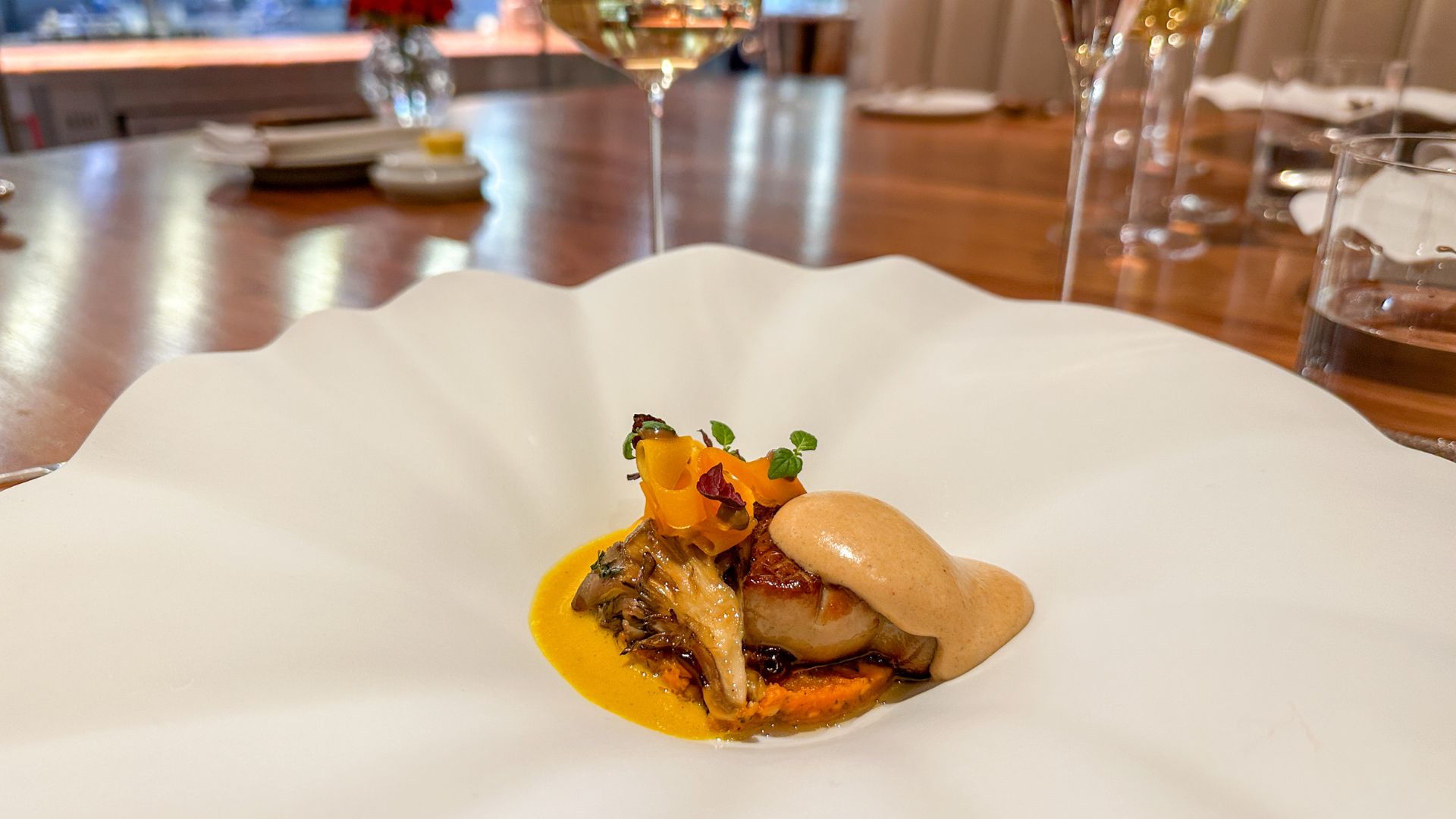 Seared foie gras served with mushrooms, purée, bright orange garnish and a light foam in a wide white bowl at Pétrus London.